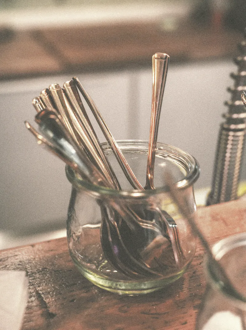 Spoons and forks standing in a glass jar on the bar