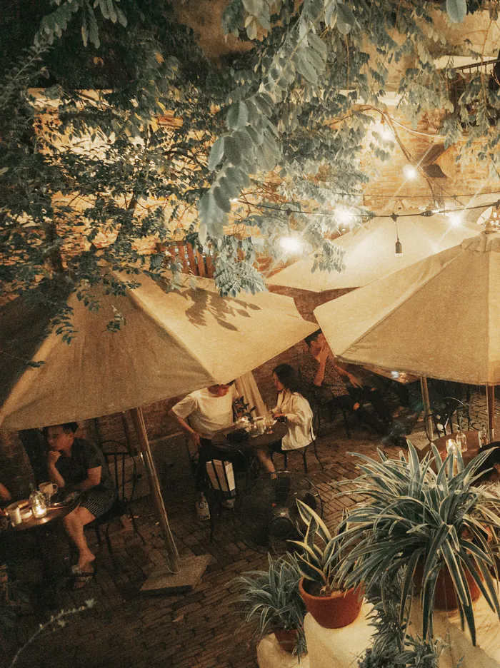 Festoon lights over the umbrellas and tables in the courtyard at night