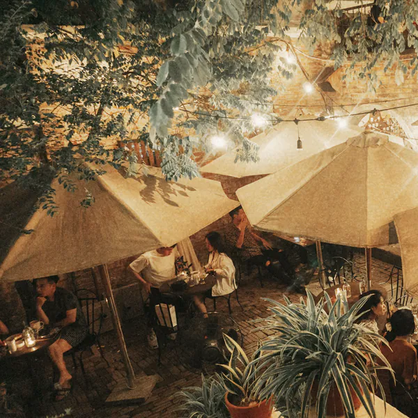 Festoon lights over the umbrellas and tables in the courtyard at night