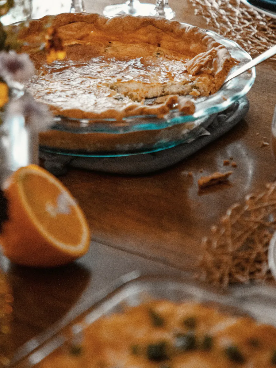 A tart, a candle and half an orange at the end of the long table
