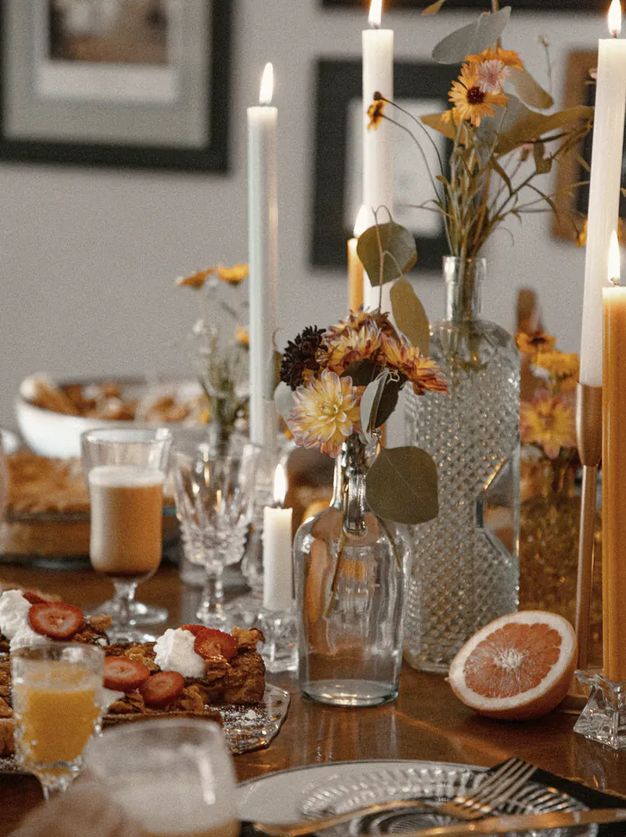 Tall candles and autumn flowers down the long table, half a grapefruit beside them