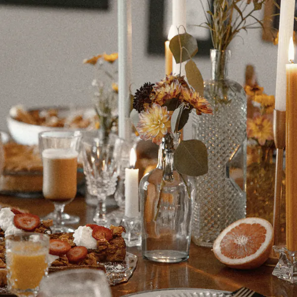 Tall candles and autumn flowers down the long table, half a grapefruit beside them