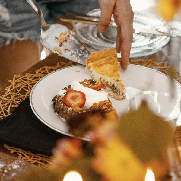 A slice of quiche served onto a plate of French toast, candles in front