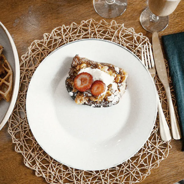A slice of French toast on a white plate with a dark napkin