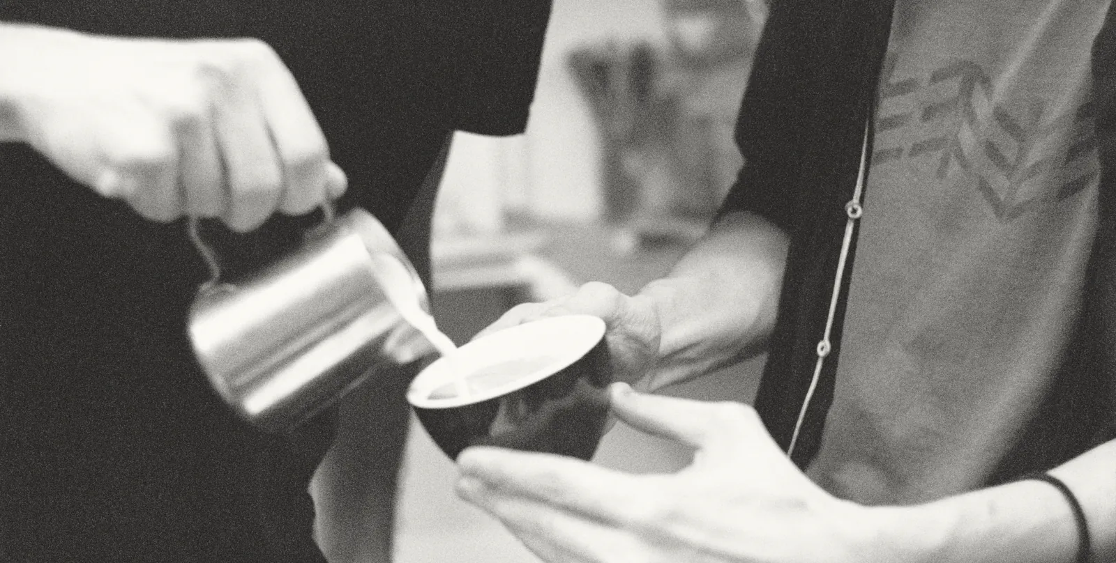 Milk poured from a steel jug into a cup held over the bar