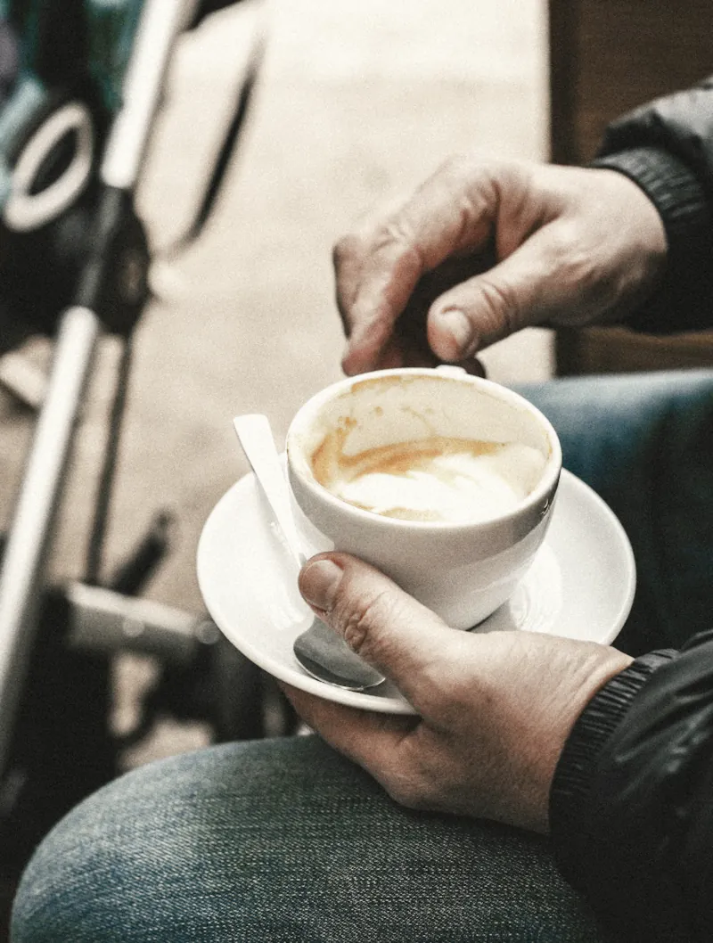 A customer holding a cup and saucer on his knee
