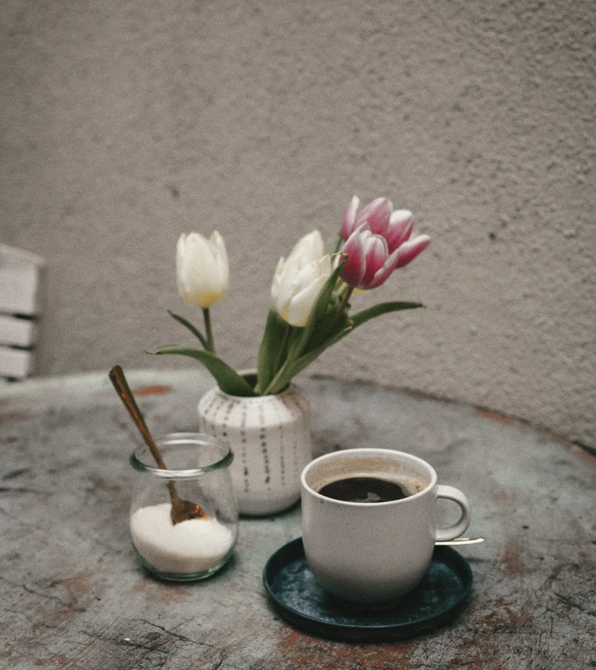 Tulips, a sugar jar and a black coffee on a chipped blue table