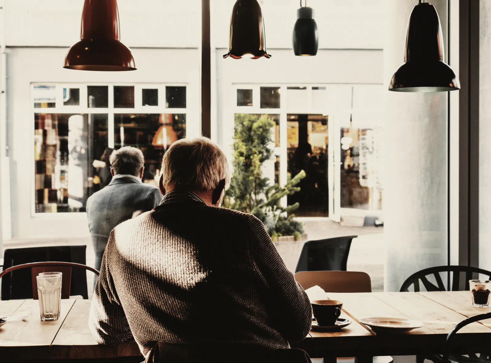 A guest at the long timber table by the window, under hanging lamps